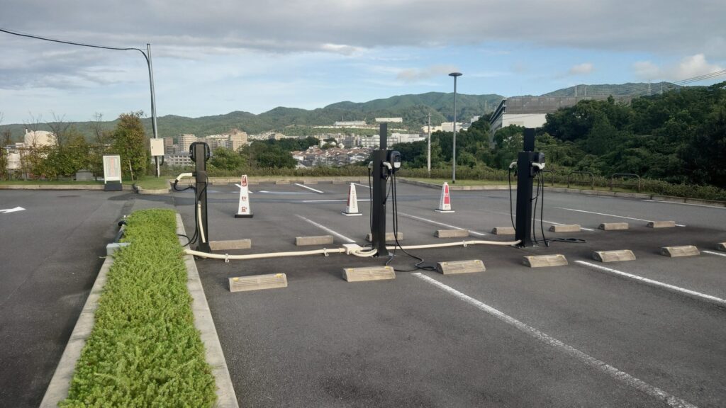 茨木国際ゴルフ倶楽部の駐車場に設置されたEV充電スタンドと遠くの山並み