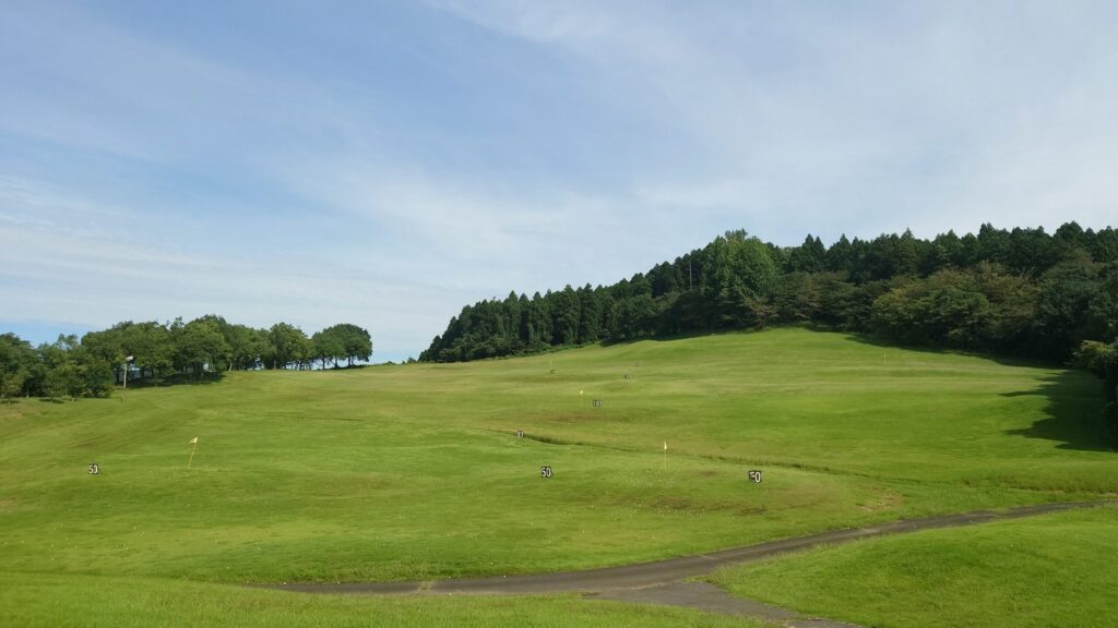 距離看板とピンフラッグが立つドライビングレンジのフィールド