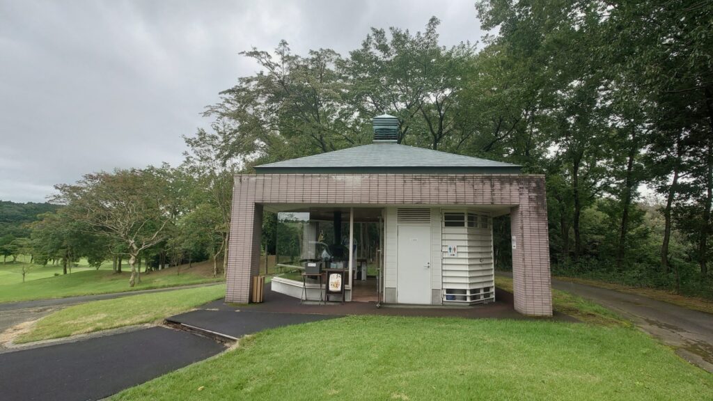 緑の木々に囲まれた売店とトイレの建物
